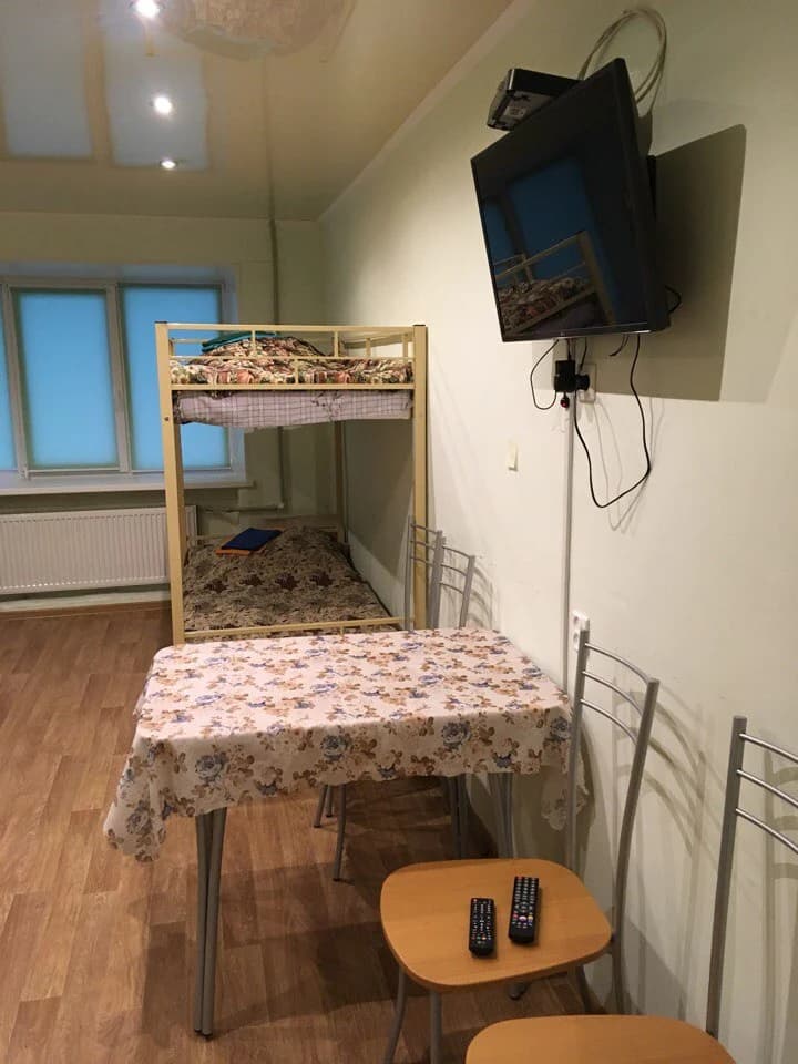 Комната хостела с двухъярусной кроватью, телевизором и столом